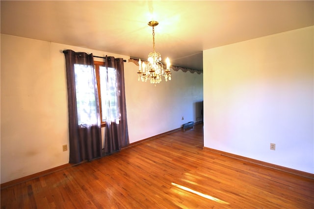 unfurnished room with a notable chandelier and hardwood / wood-style flooring