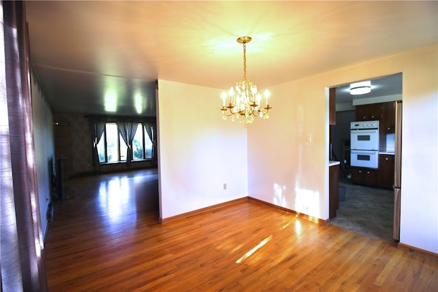 unfurnished dining area featuring dark wood-type flooring and an inviting chandelier