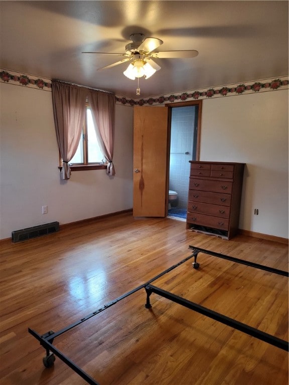 unfurnished bedroom featuring hardwood / wood-style floors, ensuite bathroom, and ceiling fan