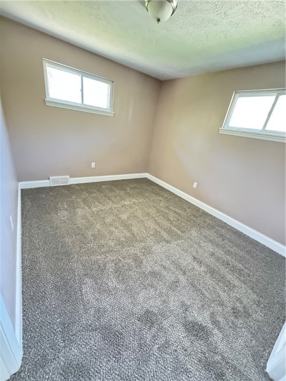 carpeted empty room with a textured ceiling