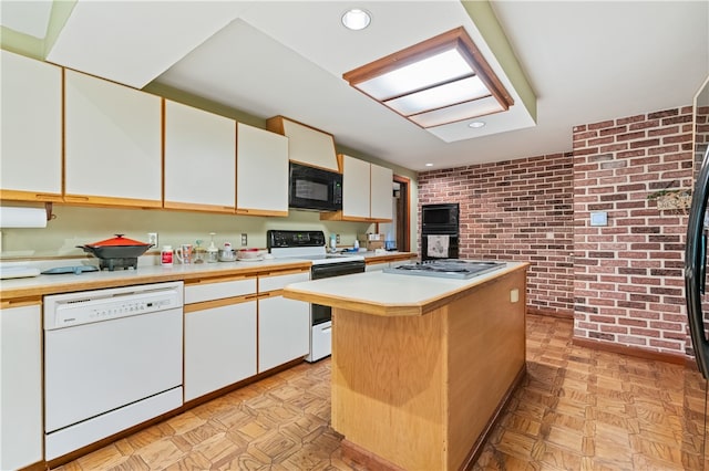 kitchen featuring light parquet flooring, white appliances, brick wall, white cabinetry, and a center island