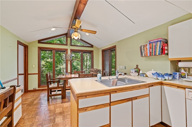 kitchen with kitchen peninsula, white cabinets, light parquet flooring, and sink