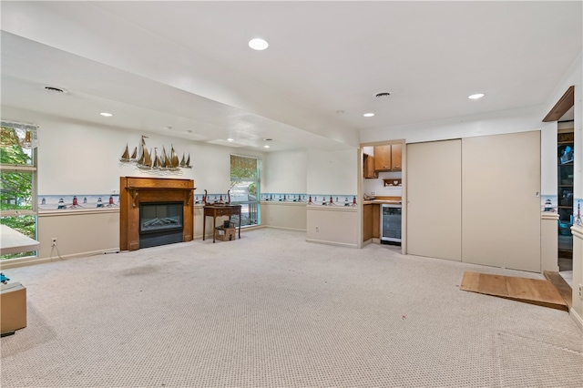 unfurnished living room featuring beverage cooler and light carpet