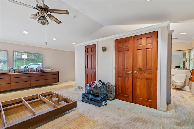 carpeted bedroom featuring ceiling fan, two closets, ensuite bath, and ornamental molding