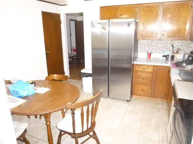 kitchen featuring stainless steel refrigerator, light tile patterned floors, and backsplash