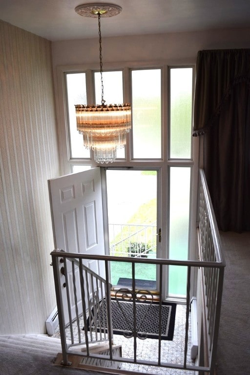 stairway featuring carpet flooring and a notable chandelier