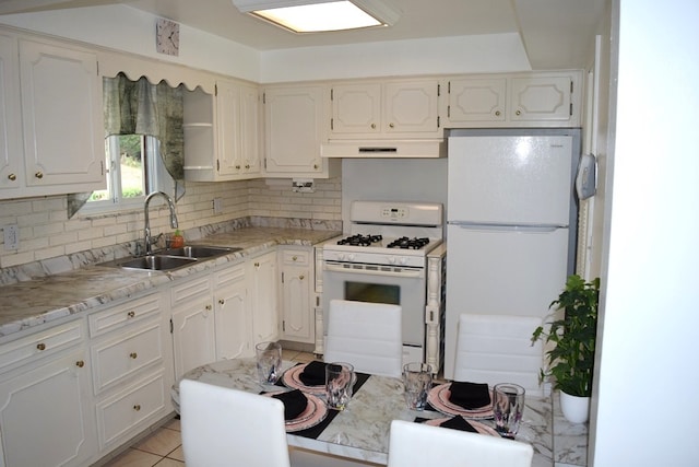 kitchen featuring light tile patterned flooring, sink, white appliances, white cabinetry, and decorative backsplash