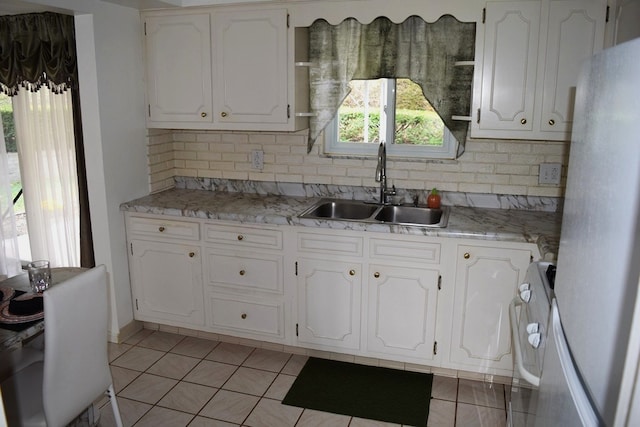 kitchen featuring light tile patterned floors, sink, backsplash, white cabinetry, and white fridge