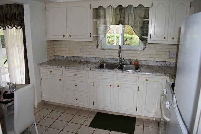 720 Pollard St, Monessen, PA 15062 - kitchen featuring a sink, decorative backsplash, freestanding refrigerator, and white cabinetry