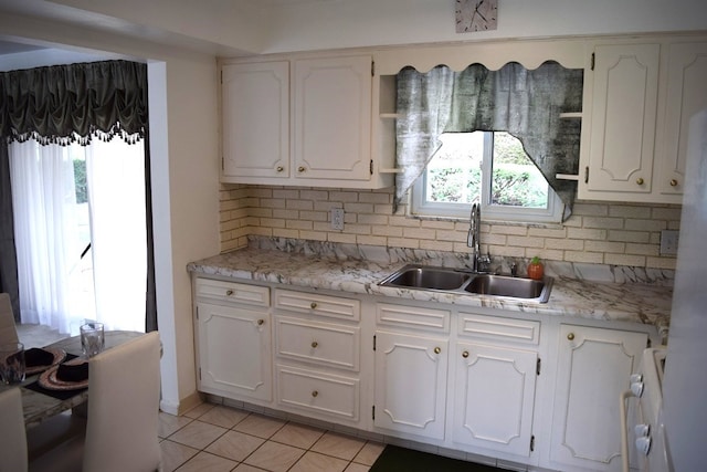 kitchen featuring tasteful backsplash, light tile patterned flooring, white cabinets, and sink