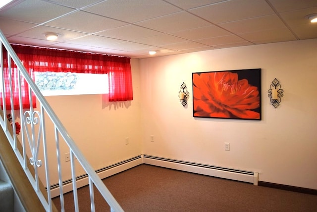 basement with a drop ceiling, baseboard heating, and carpet flooring