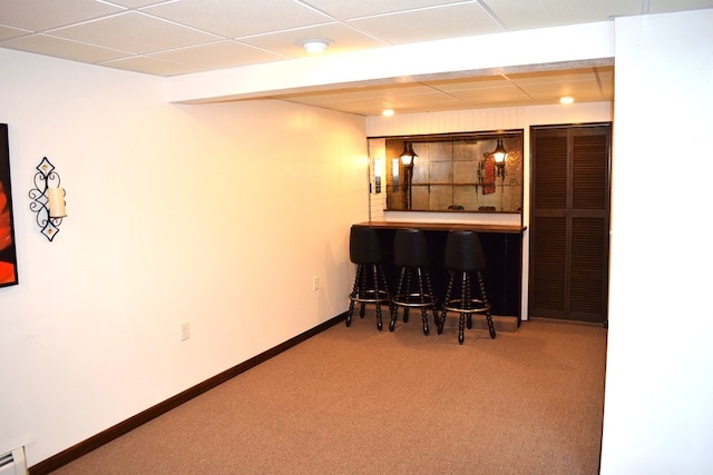 bar featuring a paneled ceiling, carpet flooring, and a baseboard heating unit