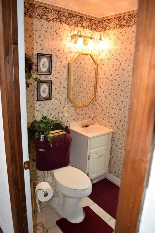 720 Pollard St, Monessen, PA 15062 - half bathroom with crown molding, tile patterned floors, vanity, toilet, and wallpapered walls