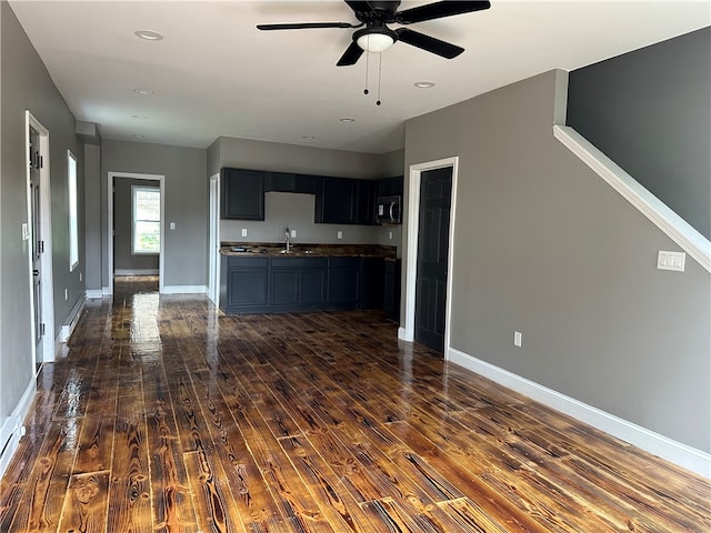 unfurnished living room featuring ceiling fan, dark wood-type flooring, and sink