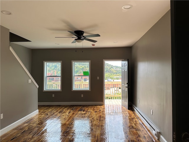 unfurnished room featuring dark hardwood / wood-style flooring, ceiling fan, and baseboard heating