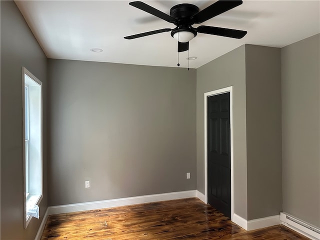 spare room featuring ceiling fan, baseboard heating, and dark hardwood / wood-style flooring