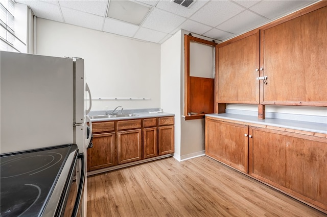 kitchen with sink, range, a drop ceiling, light wood-type flooring, and white fridge