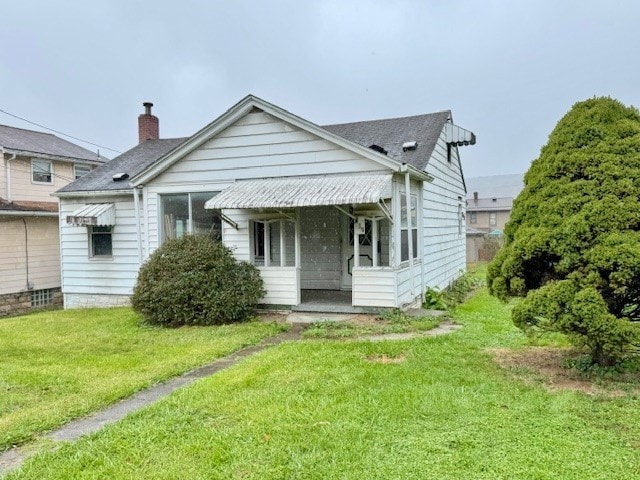 rear view of property featuring a lawn