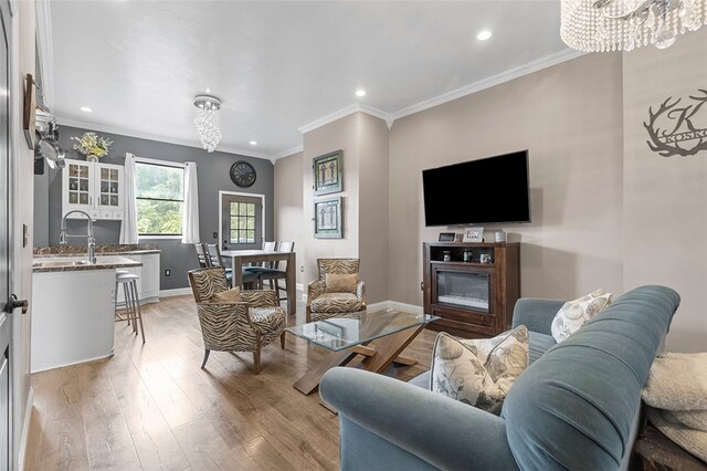 living room with light hardwood / wood-style flooring, crown molding, and a notable chandelier