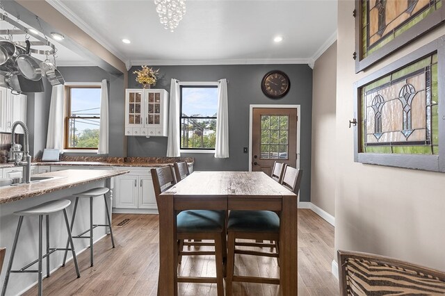 dining room featuring light hardwood / wood-style floors, a notable chandelier, sink, and ornamental molding