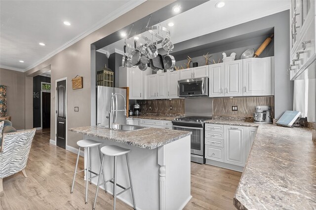 kitchen with white cabinetry, an island with sink, light hardwood / wood-style floors, and stainless steel appliances