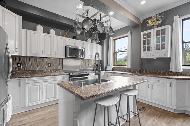 kitchen featuring white cabinetry, a healthy amount of sunlight, a center island with sink, and stainless steel appliances