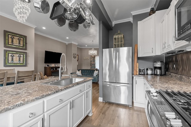 kitchen with sink, ornamental molding, white cabinetry, light wood-type flooring, and appliances with stainless steel finishes