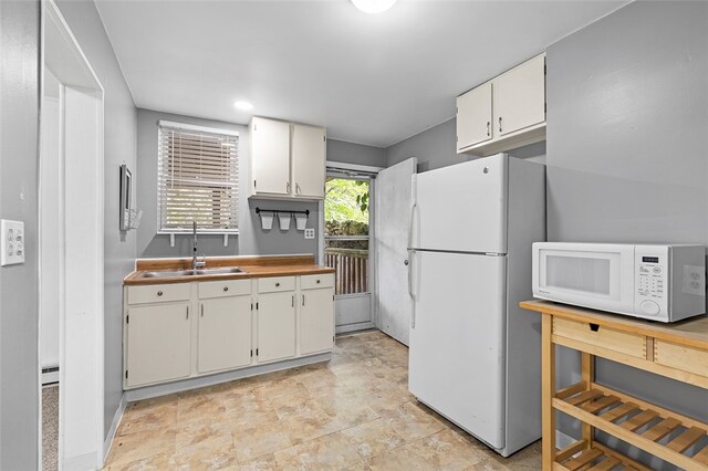 kitchen with white cabinetry, white appliances, and sink