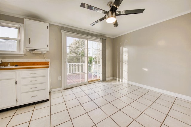 kitchen featuring ceiling fan, ornamental molding, light tile patterned floors, and white cabinetry