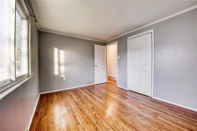 unfurnished bedroom with crown molding, a closet, and light hardwood / wood-style flooring