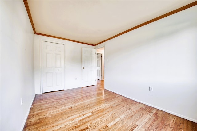 unfurnished bedroom with light wood-type flooring, crown molding, and a closet