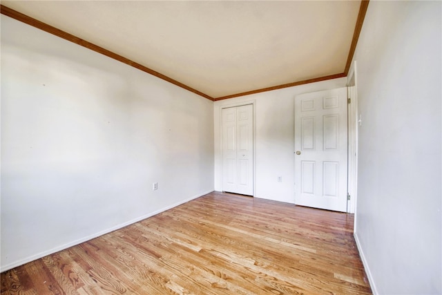 unfurnished bedroom with a closet, crown molding, and light hardwood / wood-style floors