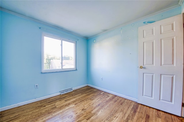 spare room with light wood-type flooring and crown molding