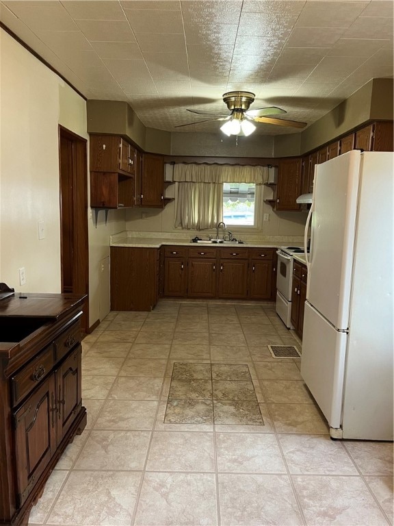 kitchen with light tile patterned flooring, ceiling fan, white appliances, dark brown cabinets, and sink