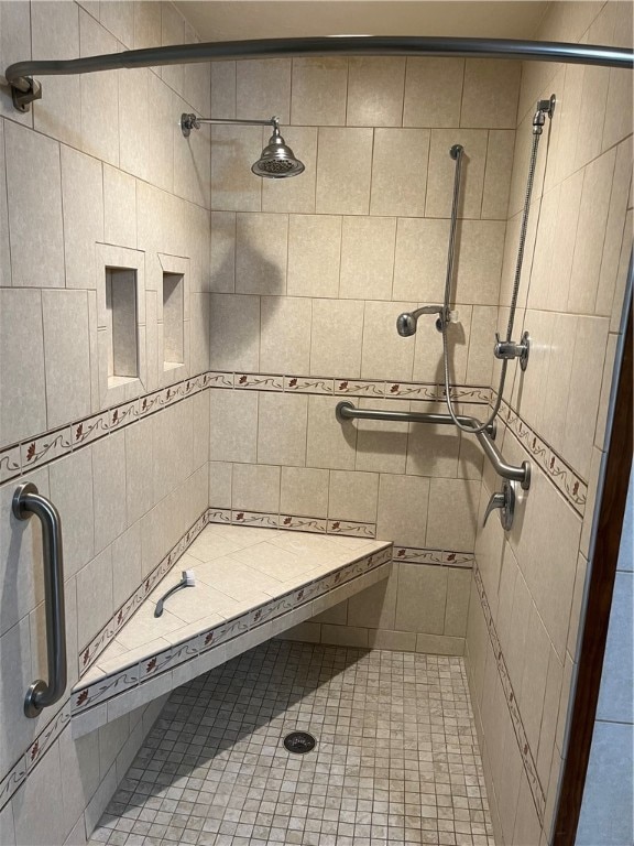 bathroom featuring tile patterned floors, a tile shower, and tile walls