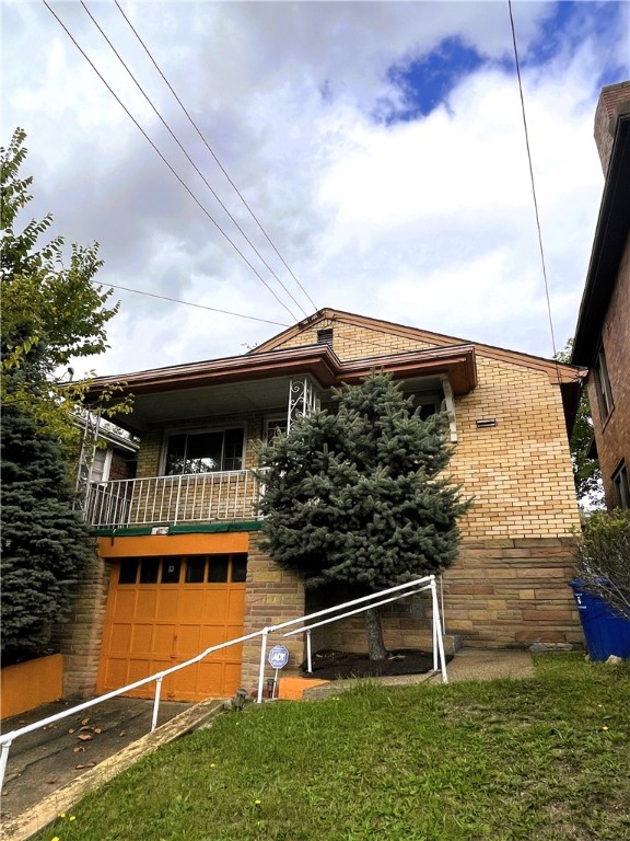 view of front of home with a garage, a front yard, and a balcony