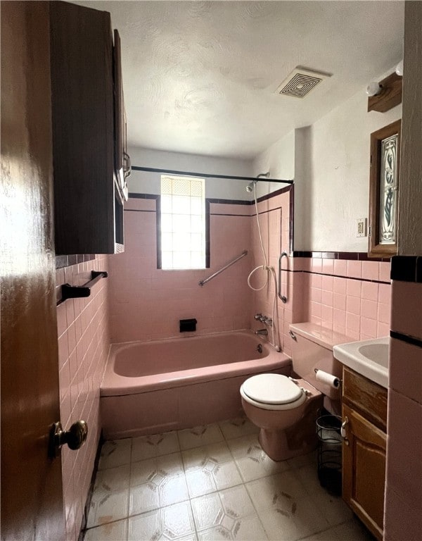 full bathroom with vanity, tile walls, tiled shower / bath combo, and toilet