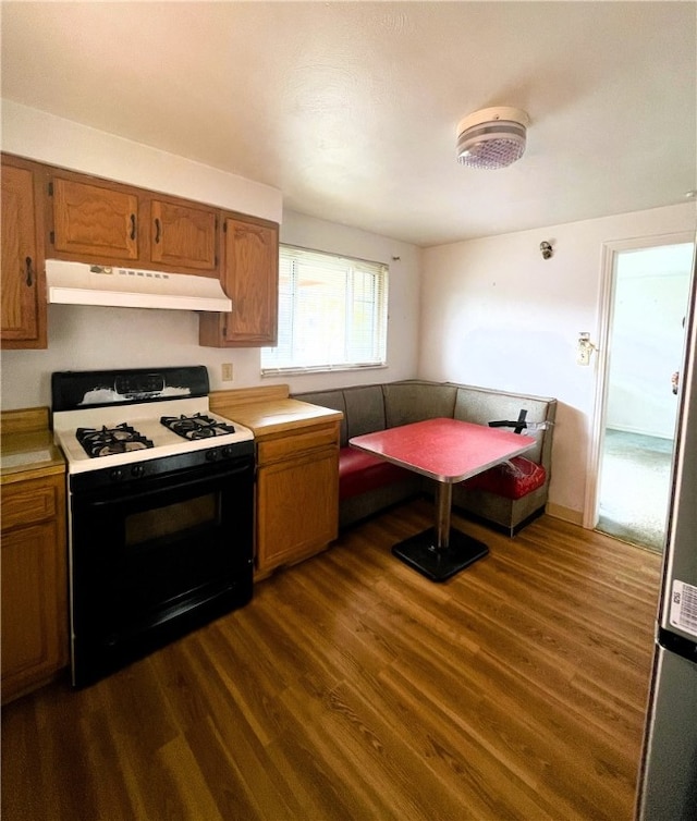 kitchen with white gas range, dark wood-type flooring, and breakfast area