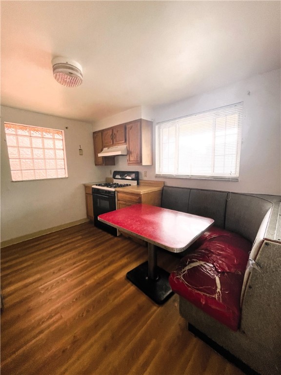 kitchen with breakfast area, white gas stove, and dark hardwood / wood-style flooring