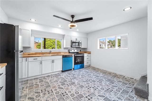 kitchen with butcher block countertops, white cabinetry, sink, and stainless steel appliances