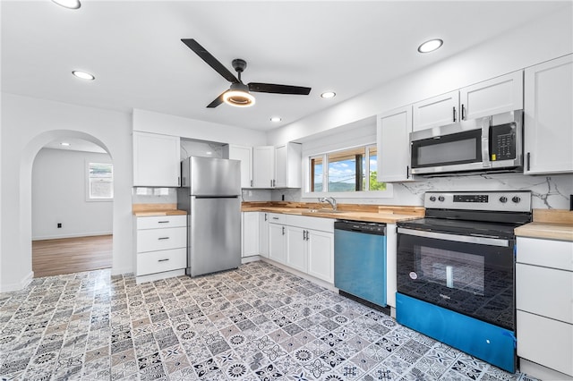 kitchen featuring white cabinets, stainless steel appliances, tasteful backsplash, and butcher block counters