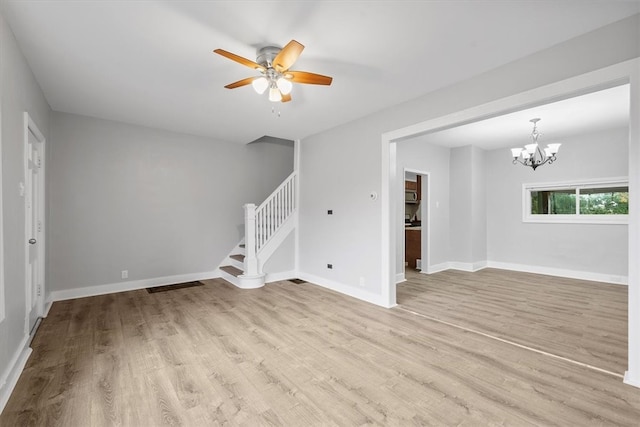 unfurnished room featuring ceiling fan with notable chandelier and light hardwood / wood-style floors