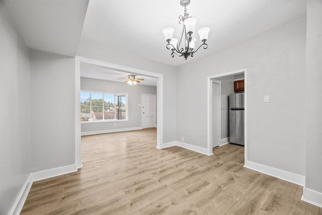 empty room with ceiling fan with notable chandelier and light wood-type flooring