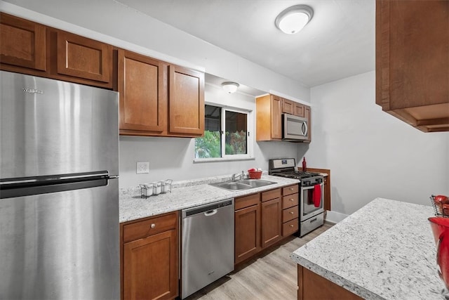 kitchen featuring light stone counters, light hardwood / wood-style floors, stainless steel appliances, and sink