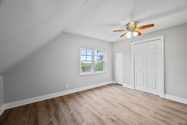 additional living space with ceiling fan, light wood-type flooring, lofted ceiling, and a textured ceiling