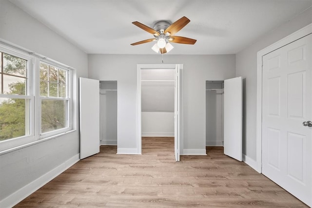 unfurnished bedroom with ceiling fan, multiple closets, and light wood-type flooring