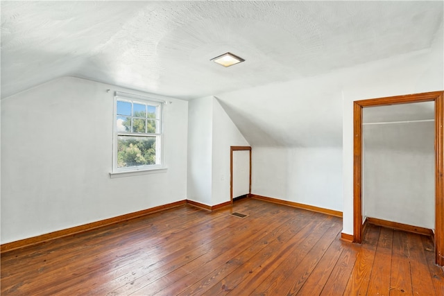 bonus room with a textured ceiling, lofted ceiling, and dark wood-type flooring