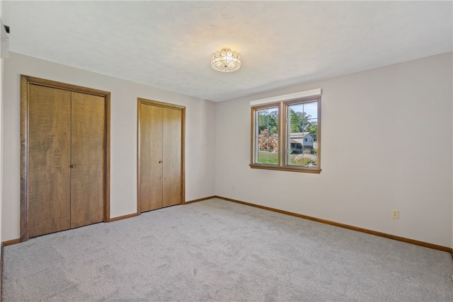 unfurnished bedroom with light carpet and two closets