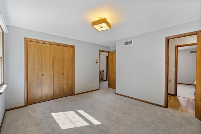 unfurnished bedroom with light carpet and a closet