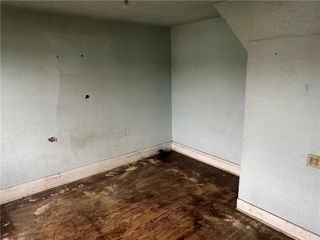 spare room featuring baseboards and wood finished floors